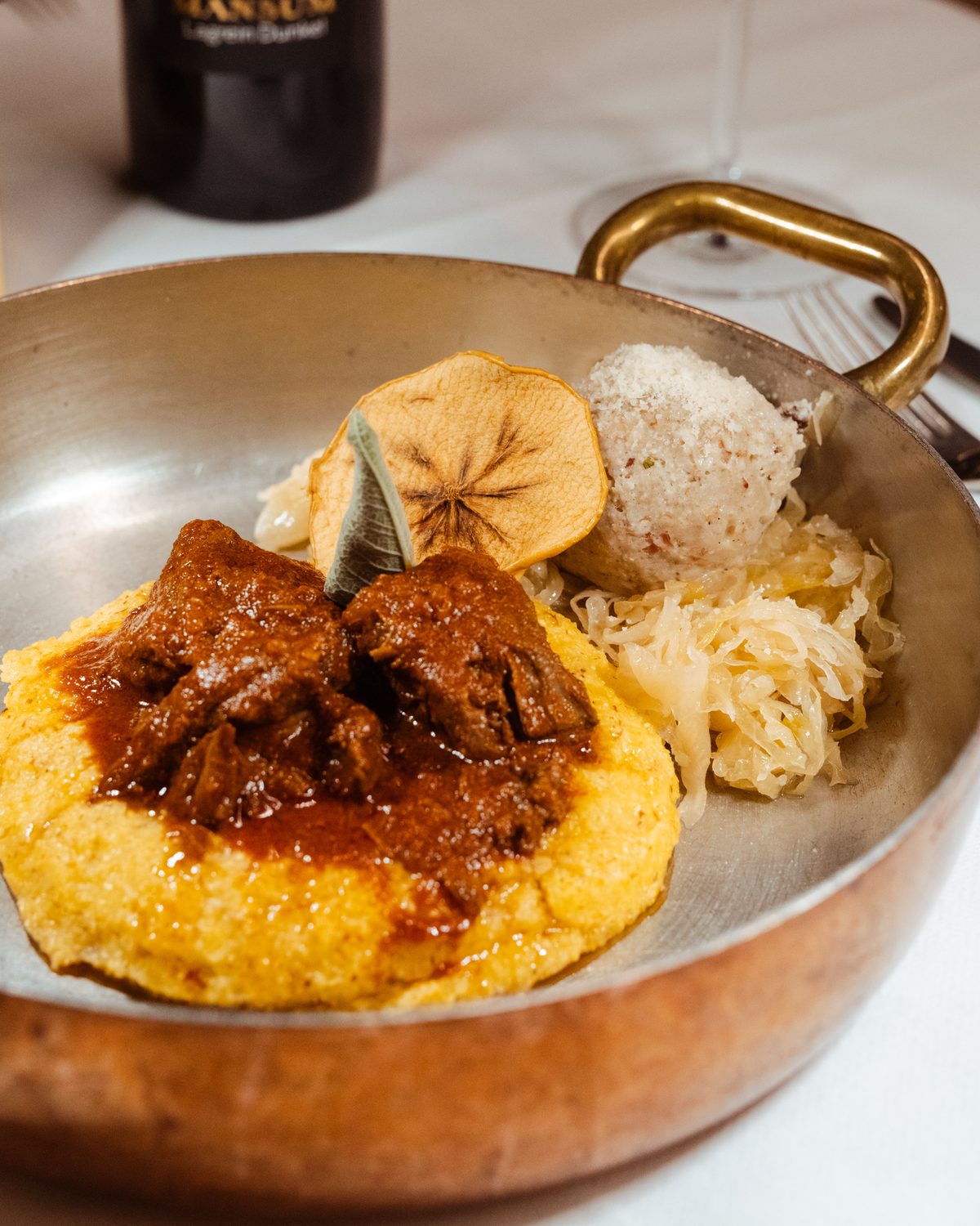 Gulasch con polenta, canederlo e crauti nella padella di rame
