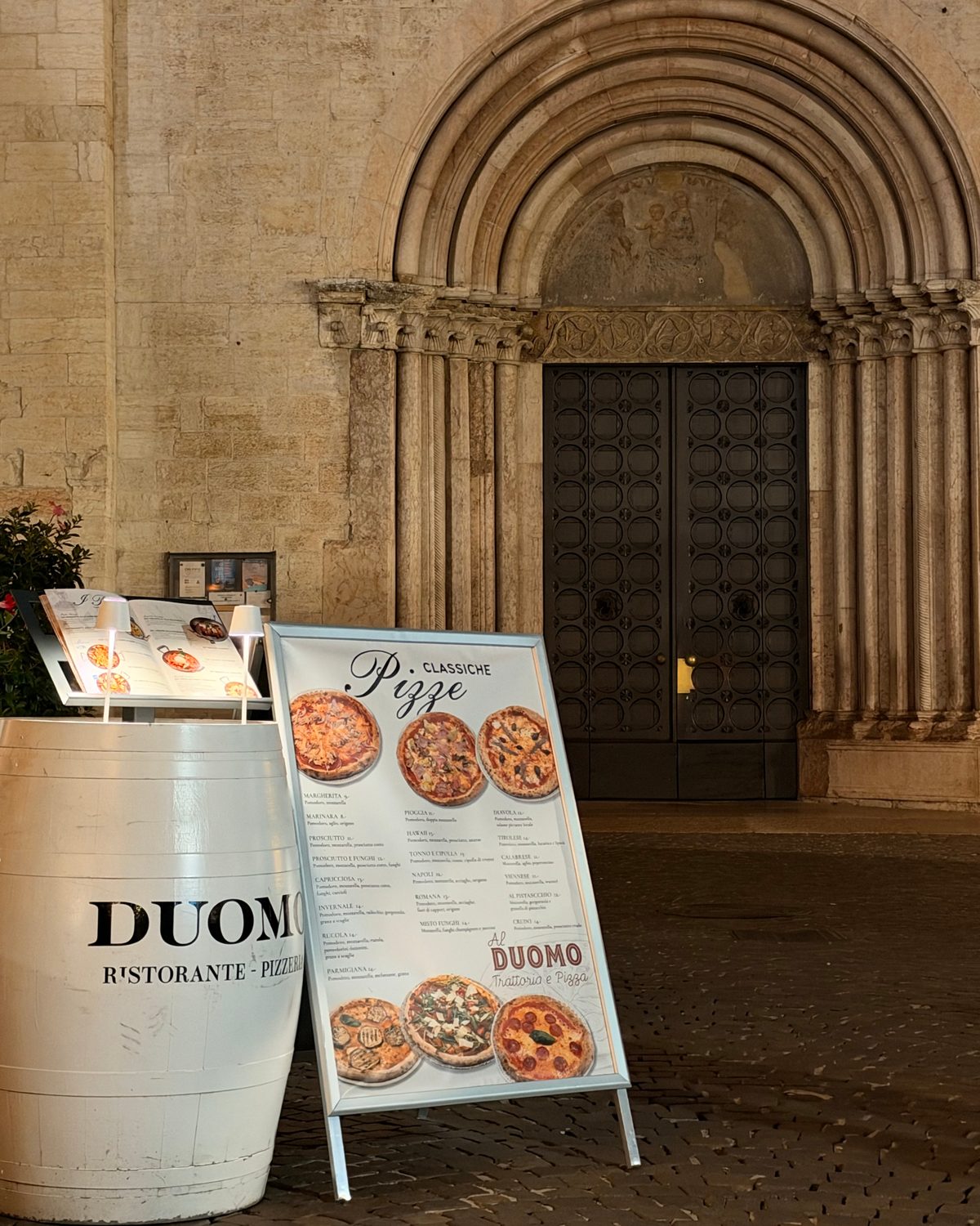 La botte con il marchio Duomo e la lavagna delle pizze davanti al portale della Cattedrale