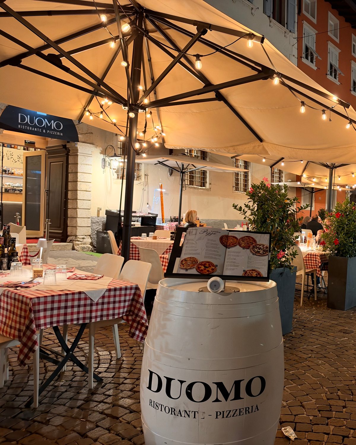 Il dehors di sera, con la botte del ristorante e gli ombrelloni accesi